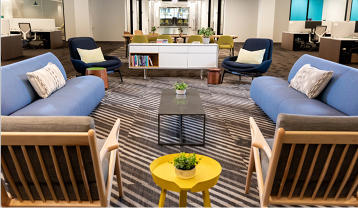 The Sprout Social office in Chicago, with a lounge area with light blue sofas, armchairs‌ and tables on a rug.