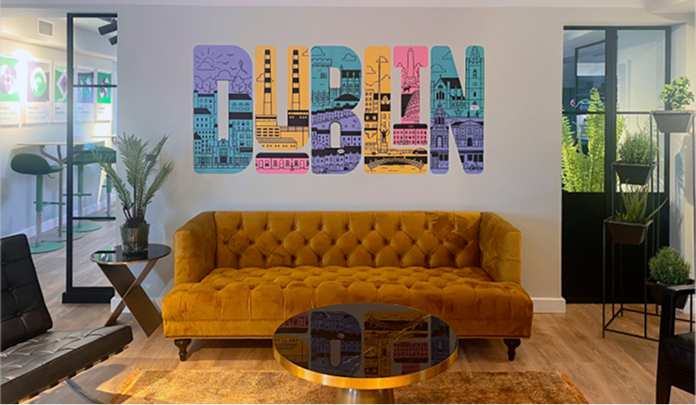 The Sprout Social office in Dublin, showing a lounge area with a sofa and two small coffee tables and a mural.